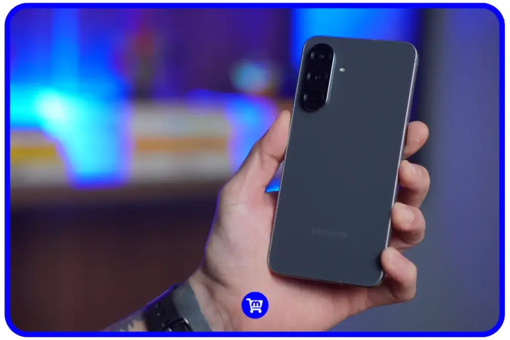 Samsung Galaxy A56 cinza sendo segurado em mão com fundo desfocado em tons azulados, mostrando a traseira com acabamento premium