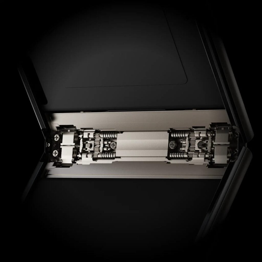 Close mecânico da dobradiça interna do Motorola Razr 70, com componentes de metal e titânio expostos contra um fundo preto.