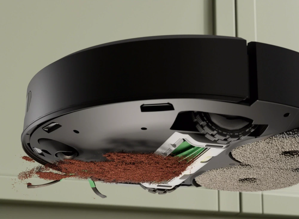 Roomba visto por baixo aspirando pó de café, com a escova emborrachada e o filtro à mostra
