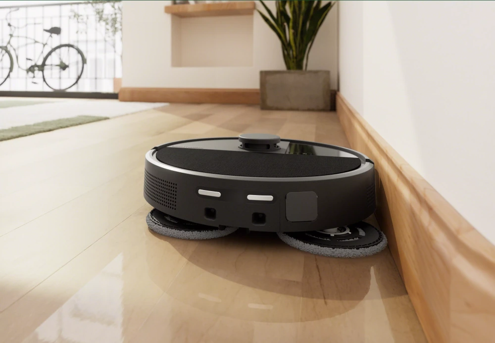 Roomba com almofadas de pano giratórias limpando rente ao rodapé no piso de madeira de uma sala