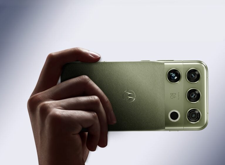 Motorola Signature 27 na cor PANTONE Capulet Olive sendo exibido na mão de uma pessoa