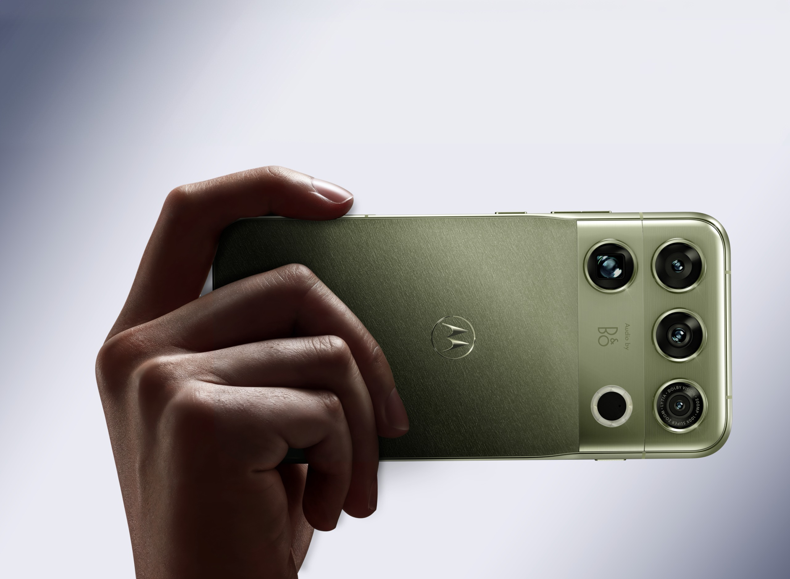 Motorola Signature 27 na cor PANTONE Capulet Olive sendo exibido na mão de uma pessoa